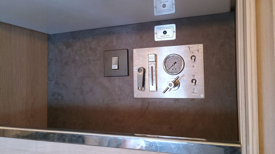 Control panel for ECHOTec watermaker in a room with gray walls and wood accents. Features gauges, switches, and labels for tank levels. Mood is technical. 